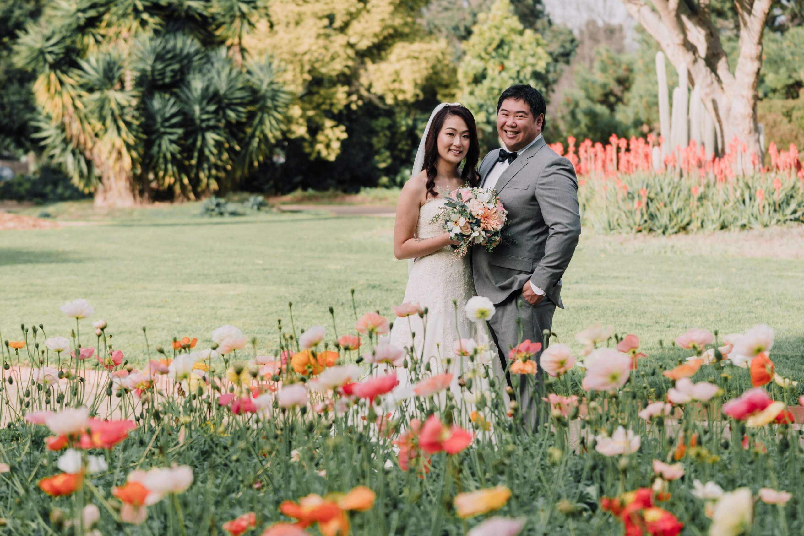 Bride and groom in a garden surrounded by blooming flowers.