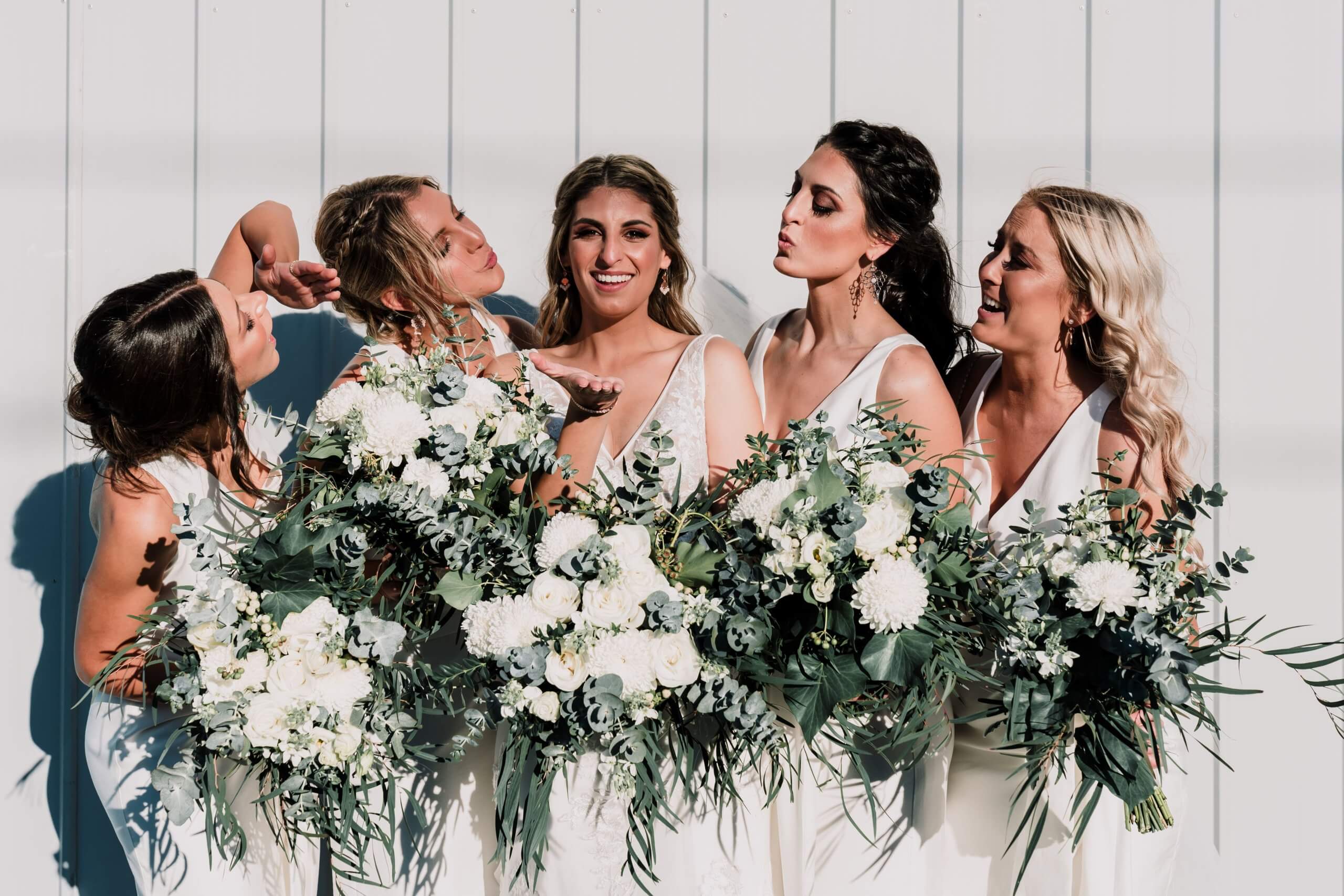 The beautiful bride in the middle and her four bridesmaids holding beautiful blooming white flowers are they are photographed during the bridal session.