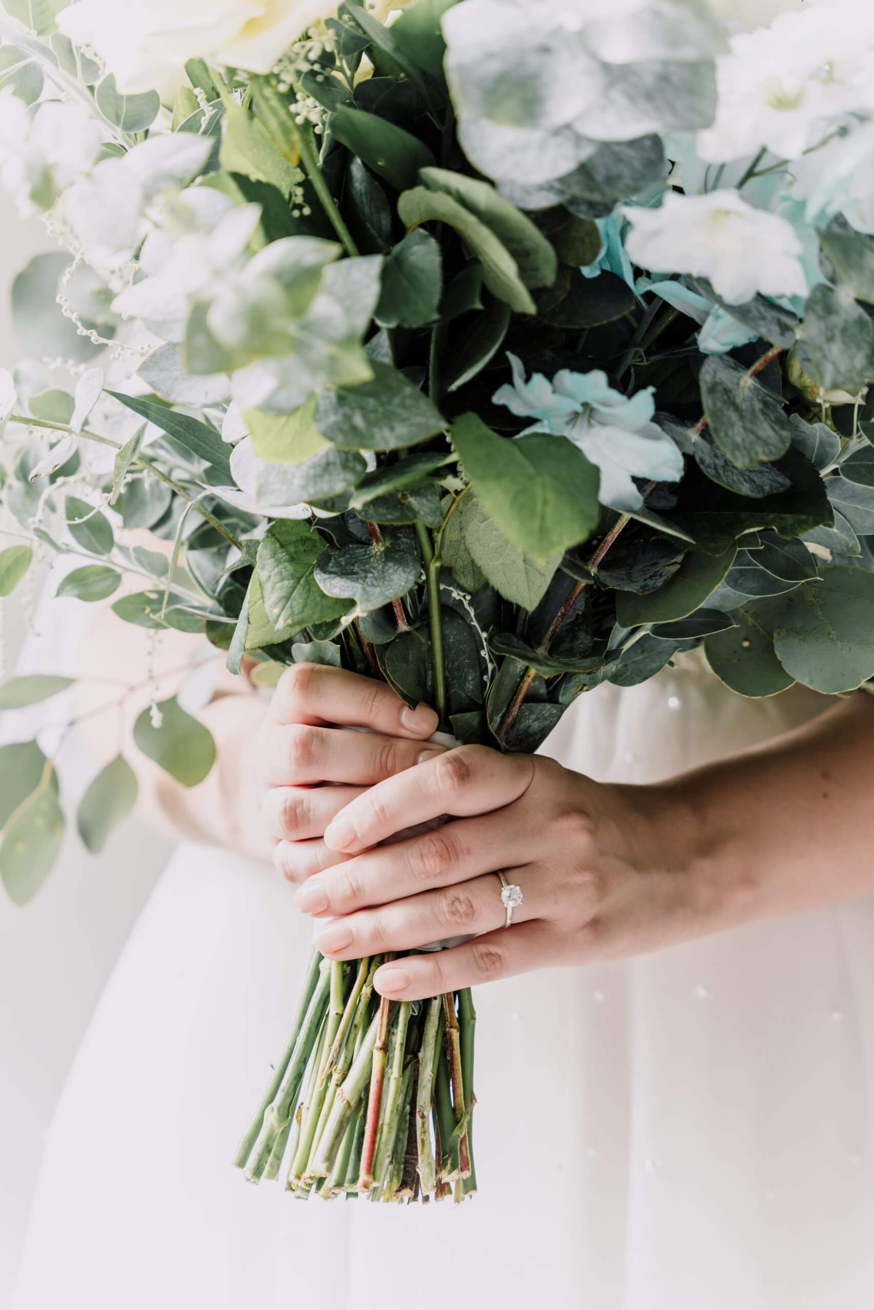 Close up photo of the bride's hands highlighting her diamond ring and beautiful wedding bouquet.