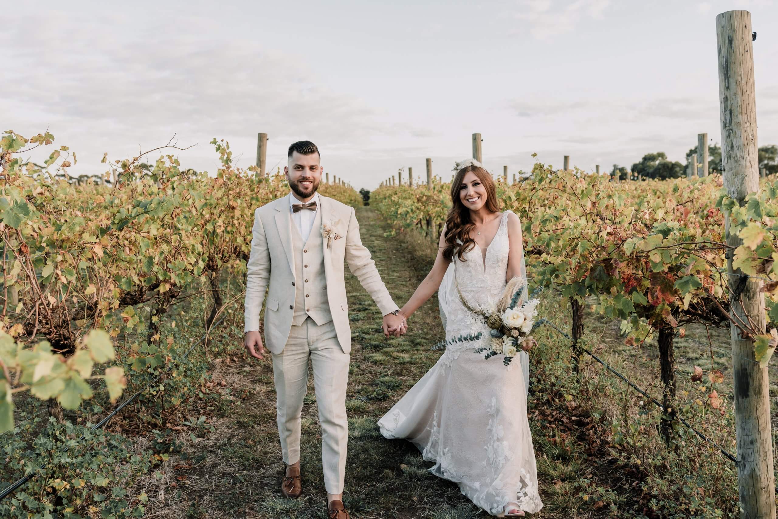 Bride and groom walking hand in hand in the vineyards at Russo Estate