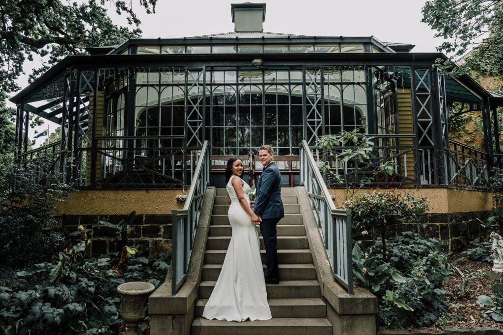 Bride and groom holding hands on the steps in front of a decorated patio