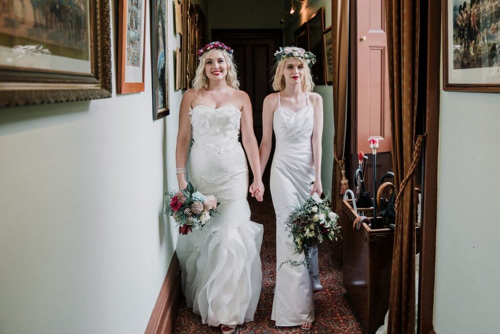 Lesbian brides walking down the hallway together and holding hands