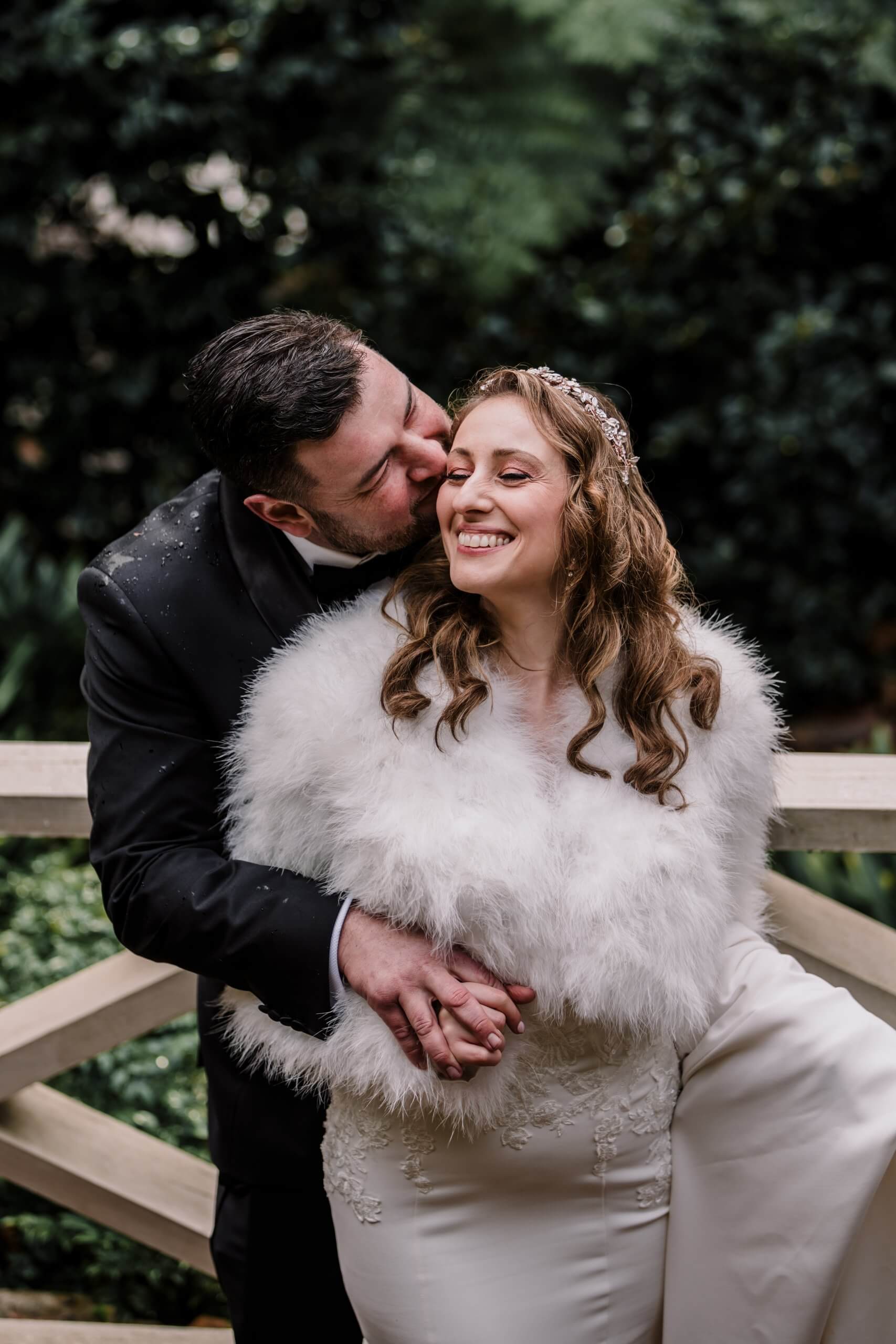 The groom kissing the bride's cheek as they pose in Nathania Springs