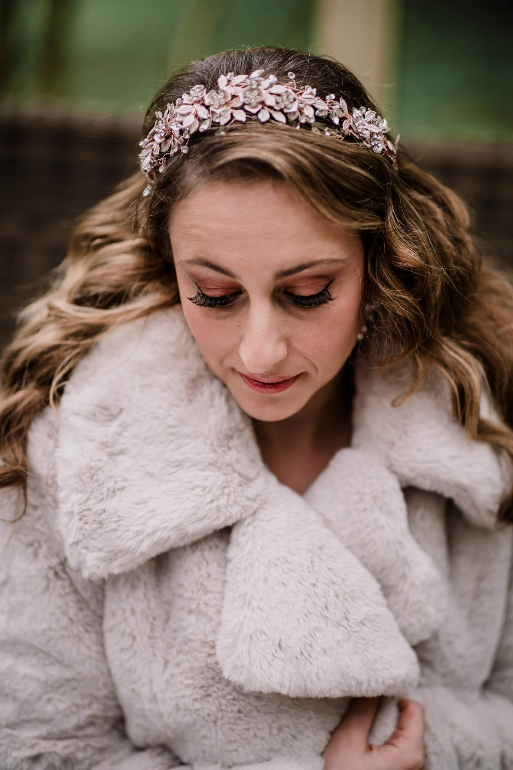 The bride looking down and wearing an intricate crown decorated with pearls