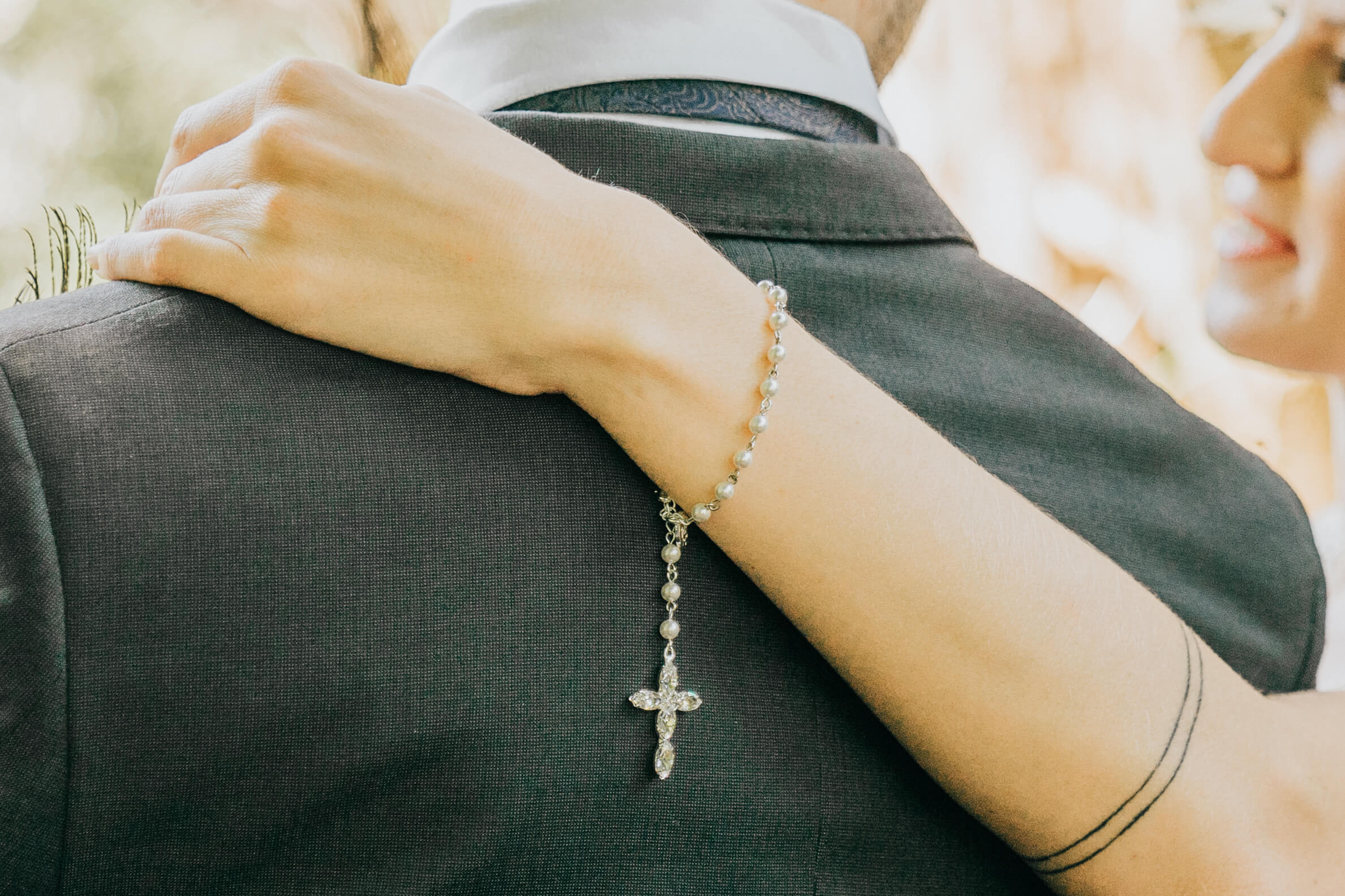 Detail shot of a rosary hanging from the bride's wrist as she holds onto the groom