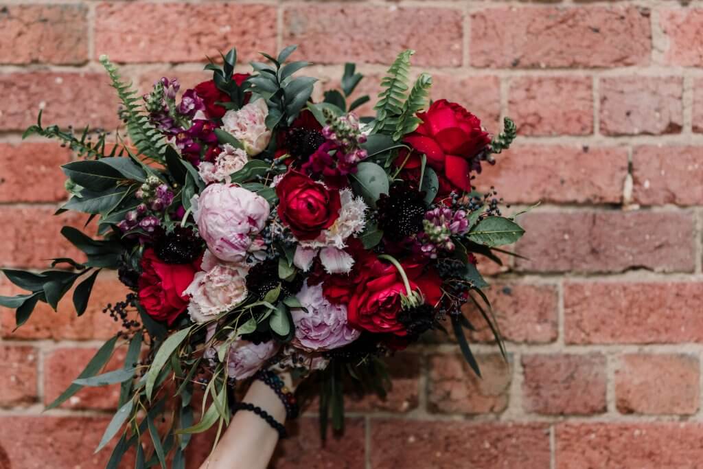 Detail shot of a bouquet of red and pink roses against a brick wall